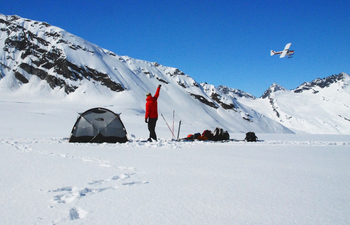 Clients wave the plane off after getting setup with their Alaska glacier ski camp at The Wall, in the Chugach outside Valdez.