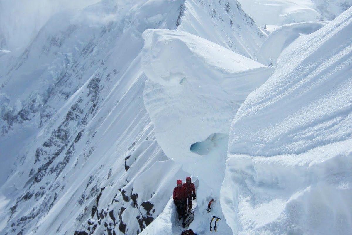 People hunker down under a cornice on Mt. Hayes.